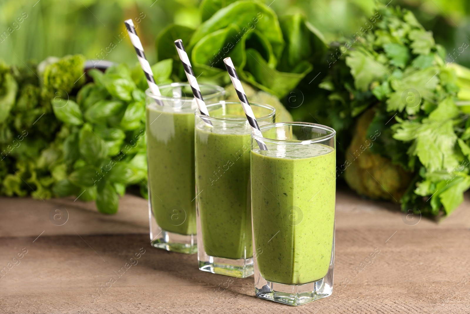 Photo of Glasses of fresh green smoothie and ingredients on wooden table