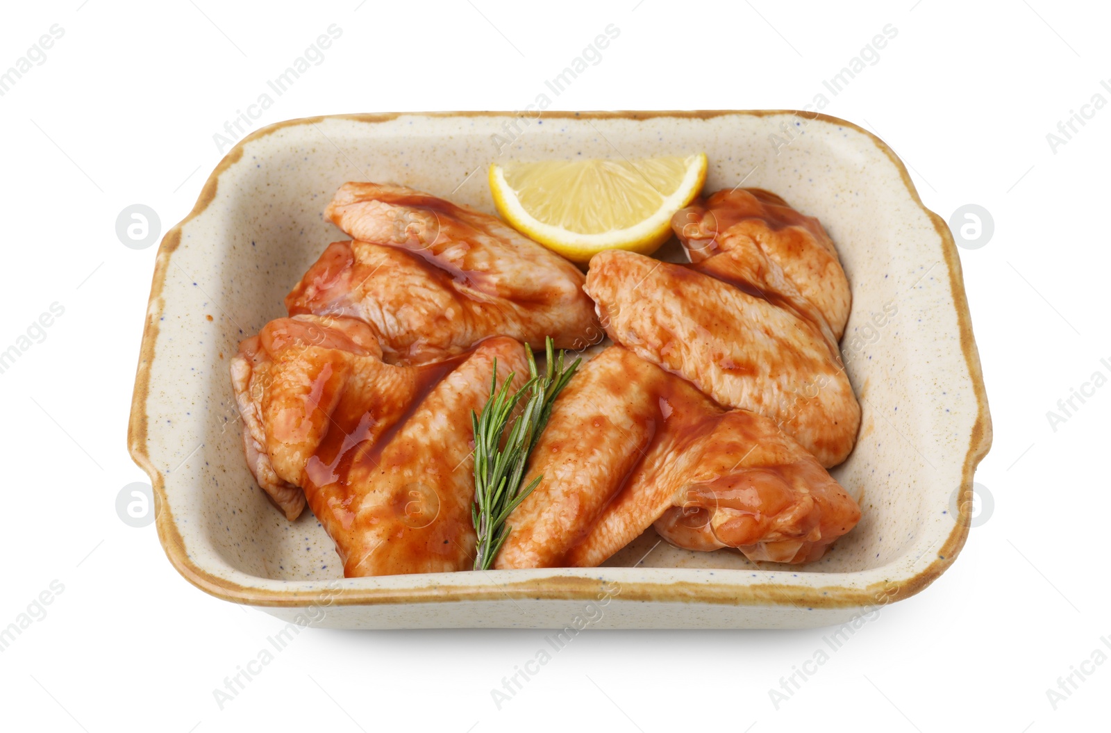 Photo of Raw marinated chicken wings, rosemary and lemon in baking dish isolated on white