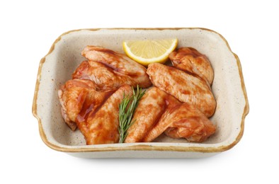 Photo of Raw marinated chicken wings, rosemary and lemon in baking dish isolated on white