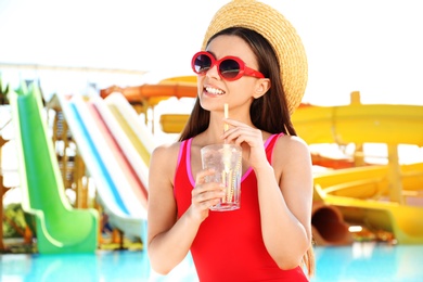 Woman with glass of refreshing drink in water park