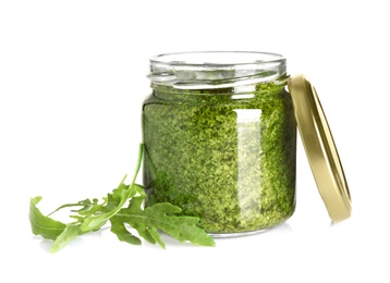 Jar of tasty pesto and arugula on white background