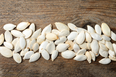 Raw pumpkin seeds on wooden background, flat lay. Vegetable planting