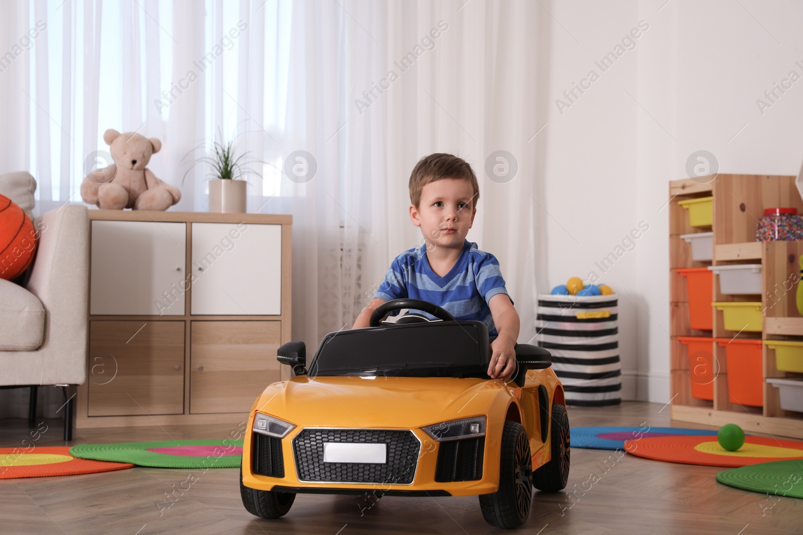 Photo of Little child playing with toy car in room