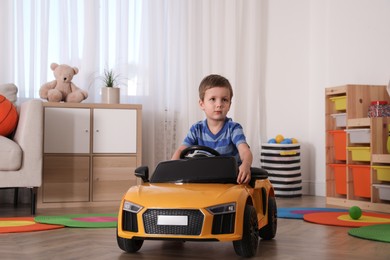 Little child playing with toy car in room