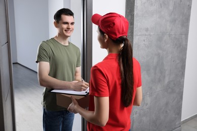 Man signing for delivered parcel from courier indoors
