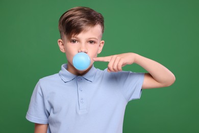 Boy blowing bubble gum on green background