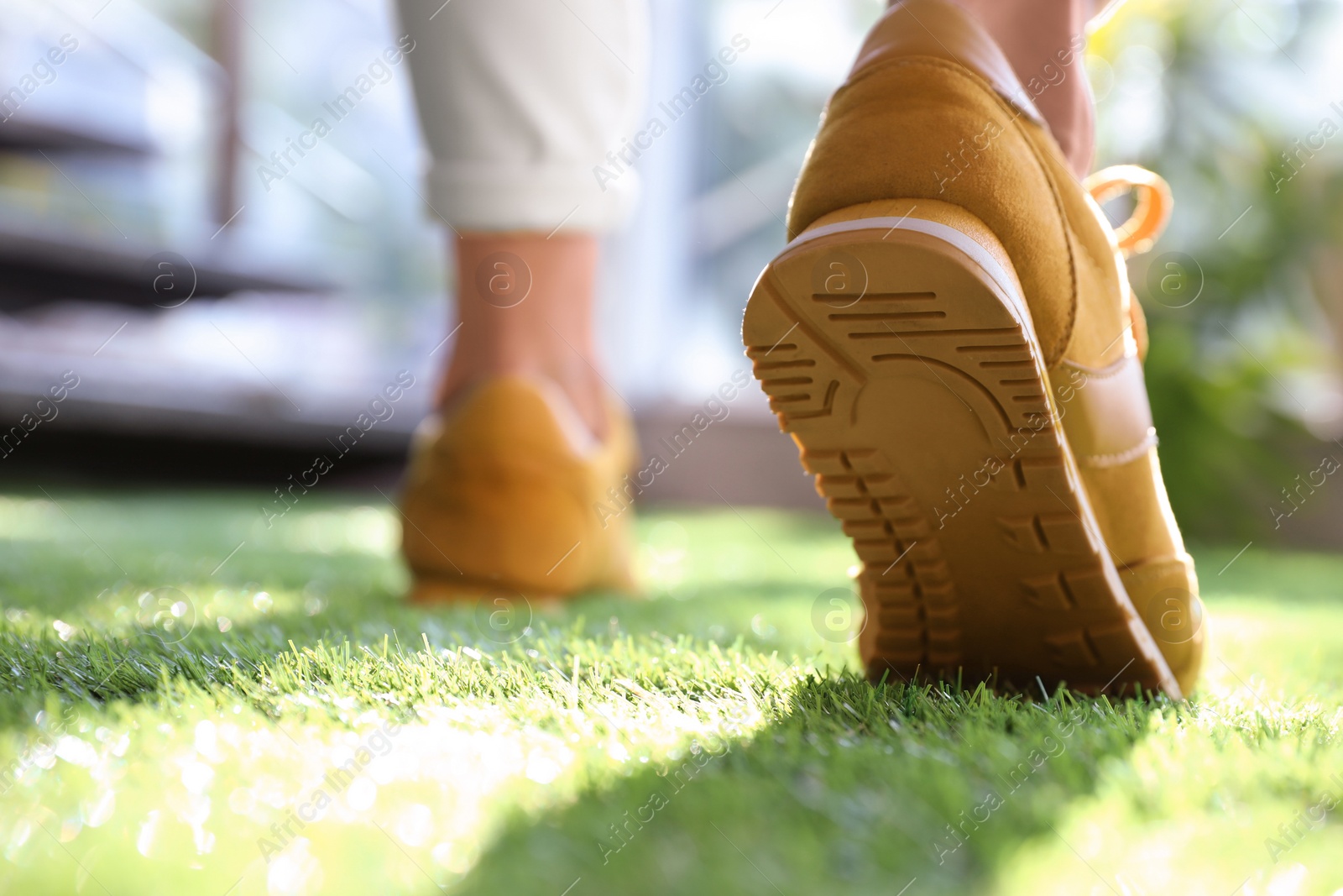 Photo of Young woman wearing stylish sneakers on green grass, closeup