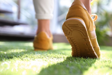 Young woman wearing stylish sneakers on green grass, closeup