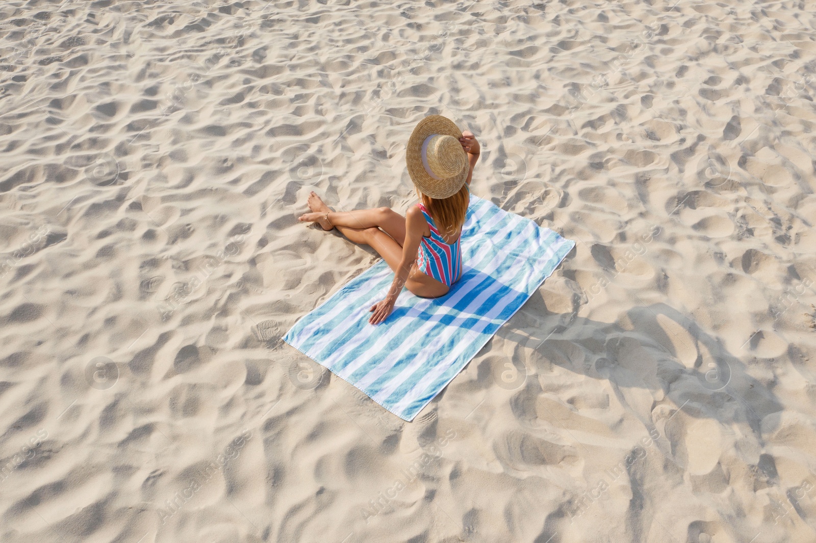 Image of Woman sunbathing on beach towel at sandy coast
