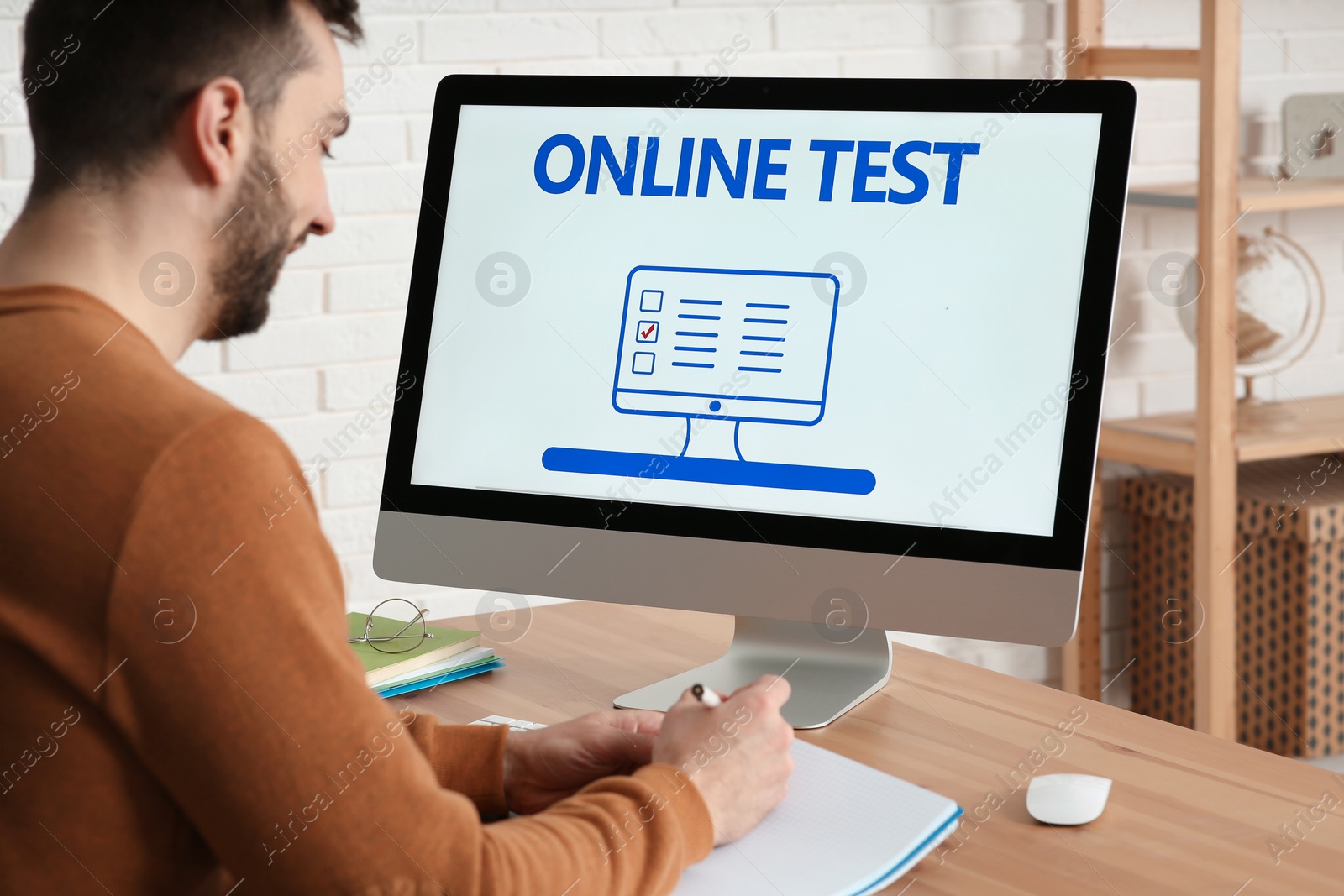 Photo of Man taking online test on computer at desk indoors