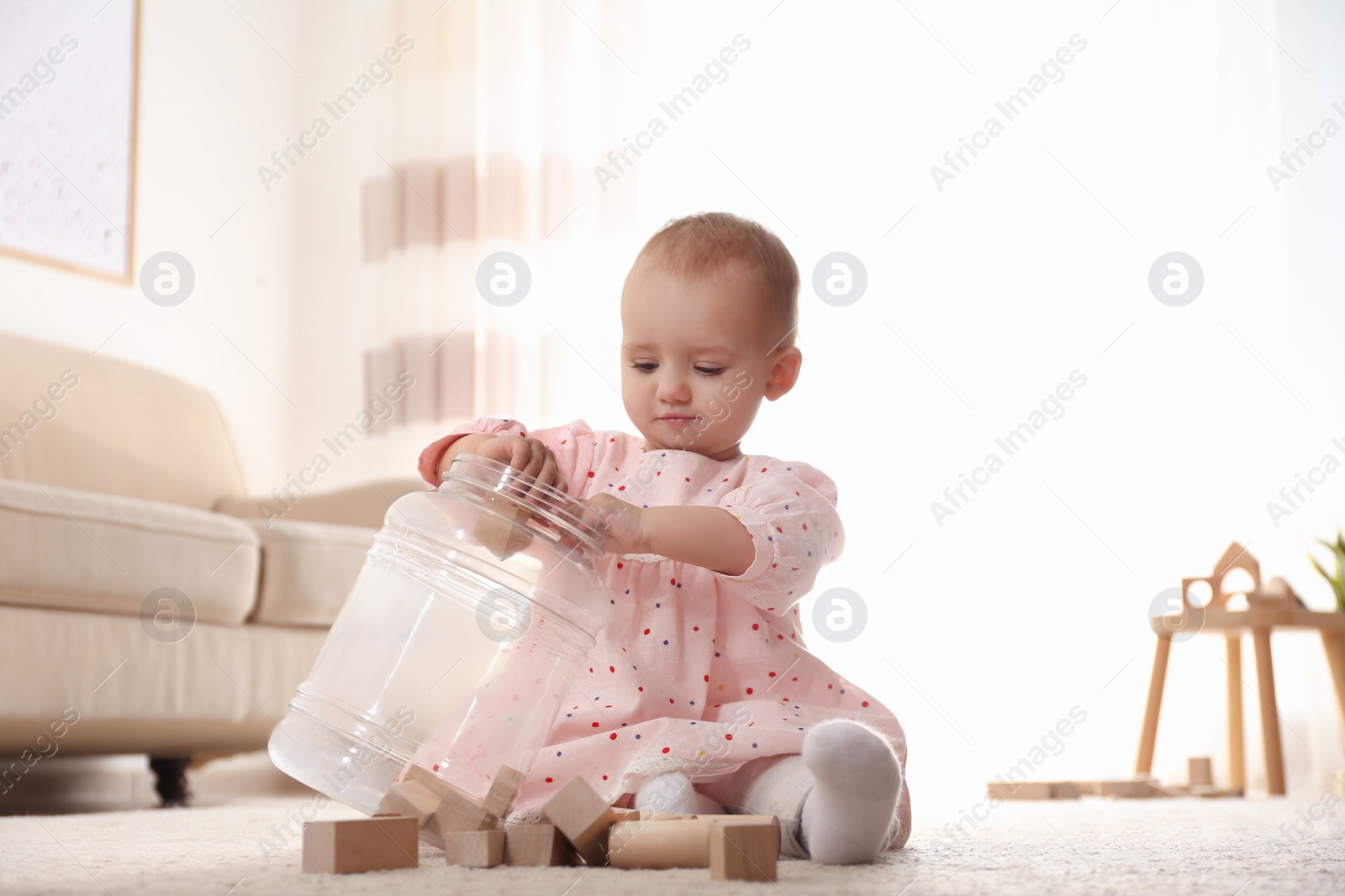 Photo of Cute child playing with wooden building blocks on floor at home