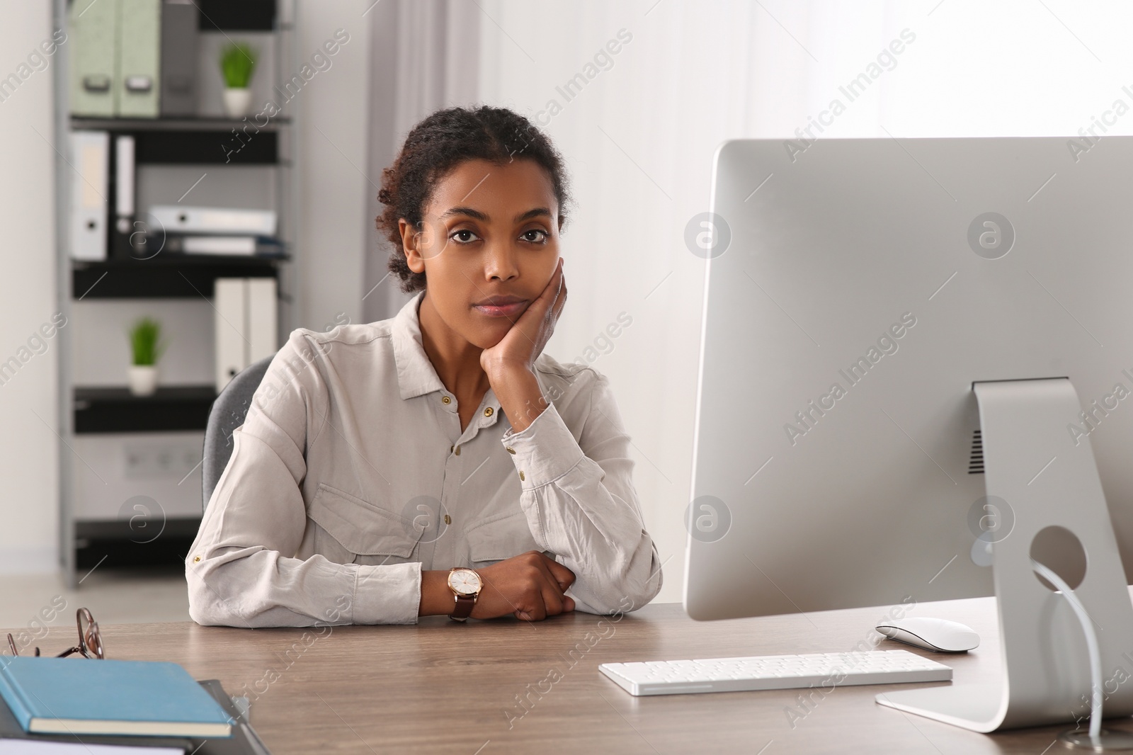 Photo of Sad African American intern at table in office. First work day