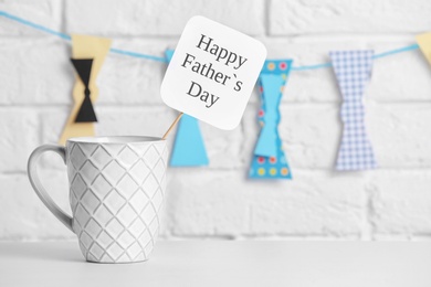 Photo of Cup on table against brick wall with hanging bow ties. Father's day celebration