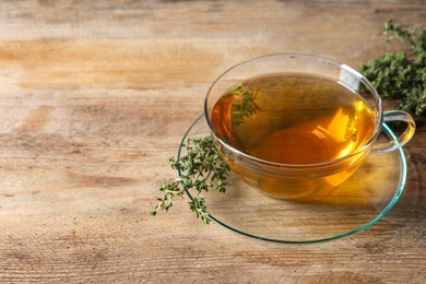 Photo of Aromatic herbal tea with thyme on wooden table, space for text