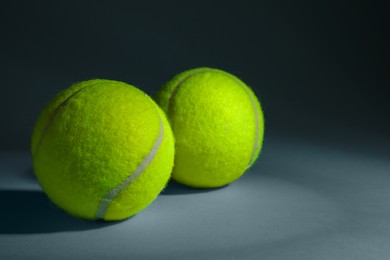 Two tennis balls on dusty light blue background, closeup. Space for text