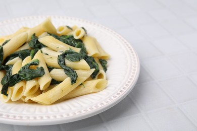 Photo of Tasty pasta with spinach and sauce on white tiled table, closeup