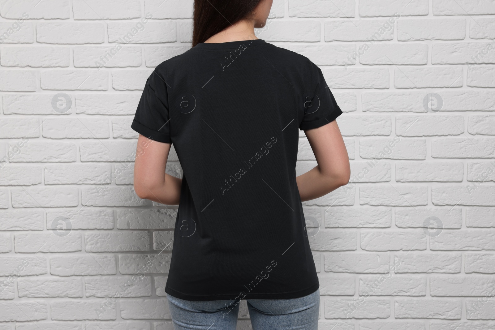 Photo of Woman wearing stylish black T-shirt near white brick wall, closeup