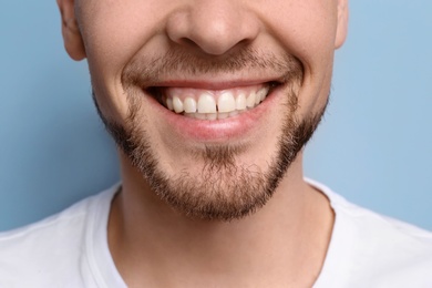 Photo of Young man with beautiful smile on grey background. Teeth whitening