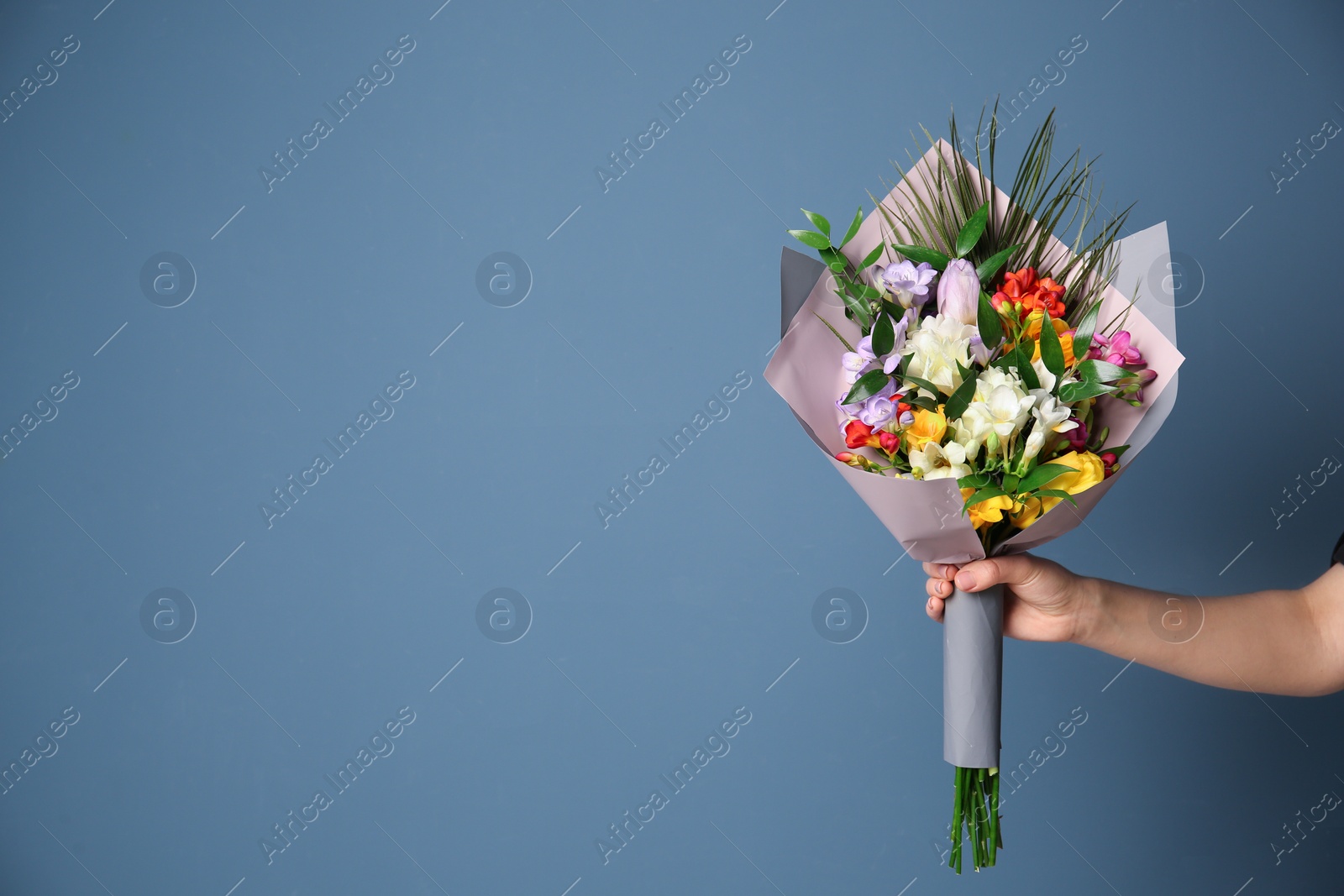 Photo of Woman with beautiful bouquet of freesia flowers on color background