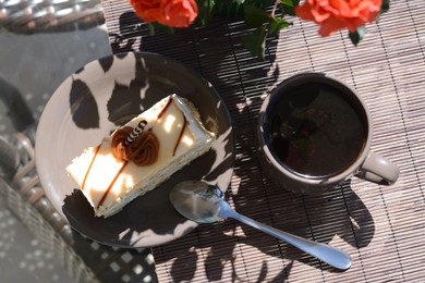 Photo of Tasty dessert, cup of fresh aromatic coffee and flowers on glass table outdoors, flat lay