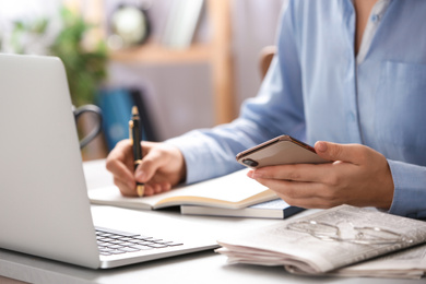 Journalist with smartphone working at table, closeup