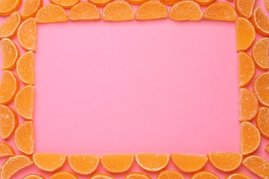 Photo of Frame made with orange marmalade candies on pink background, flat lay