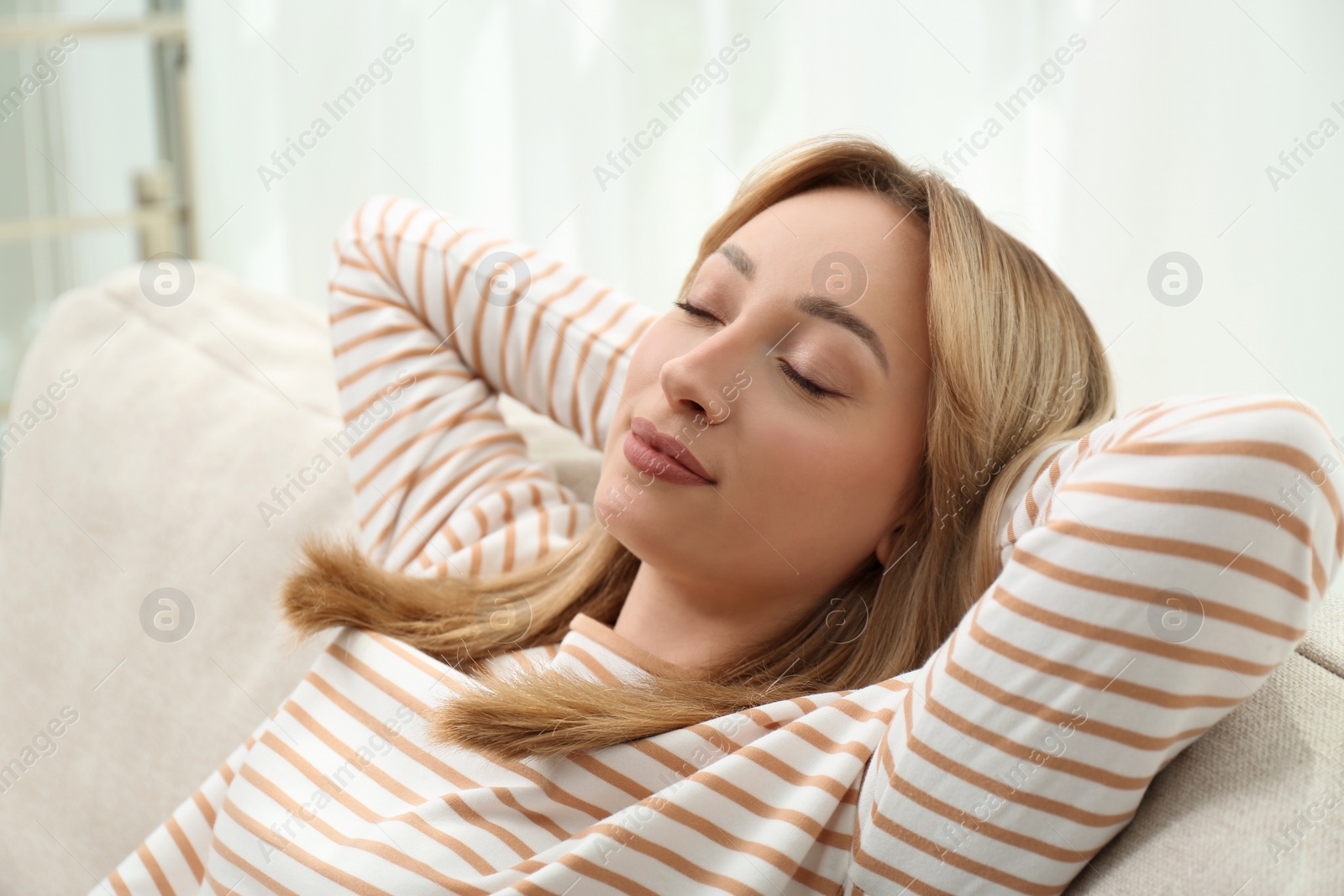 Photo of Beautiful young woman relaxing on sofa indoors