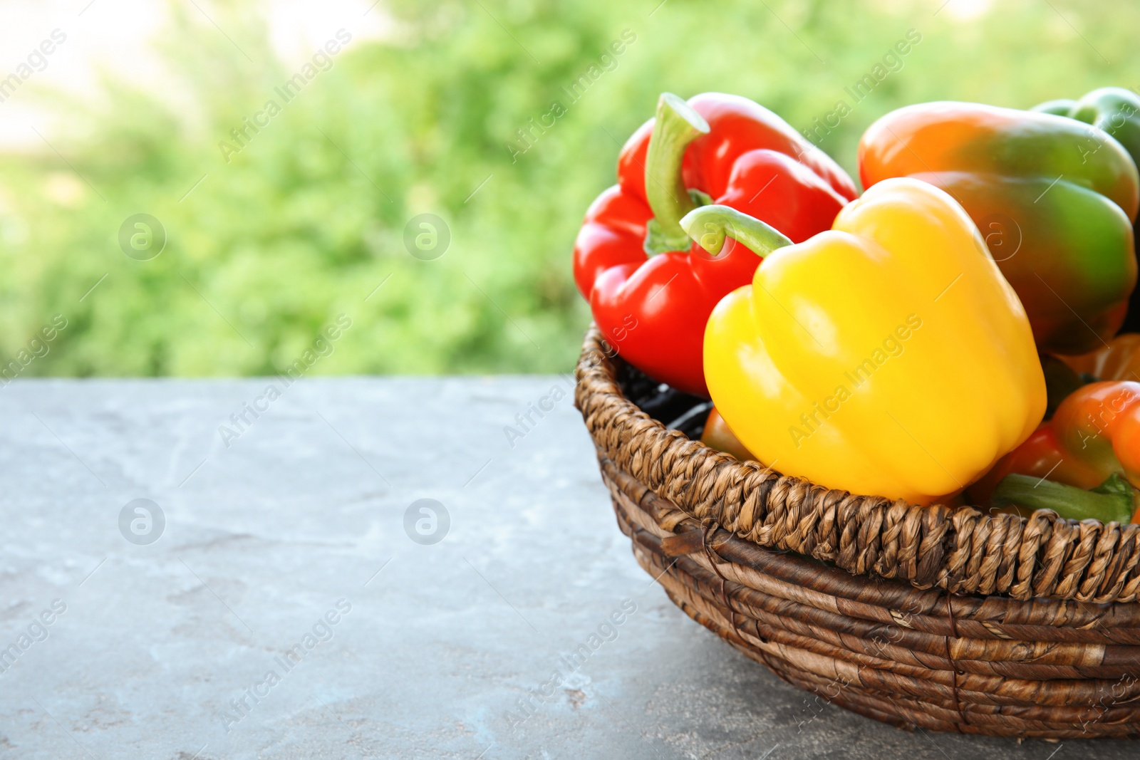 Photo of Bowl with ripe paprika peppers on table against blurred background