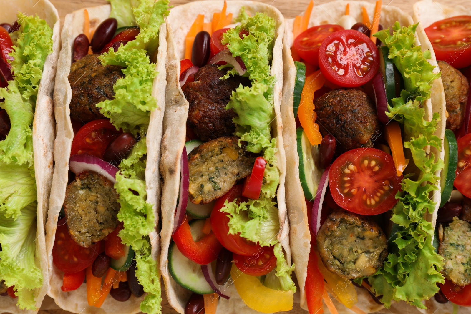 Photo of Many delicious vegetarian tacos as background, top view