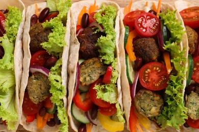 Many delicious vegetarian tacos as background, top view