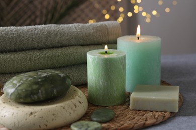 Photo of Spa composition. Burning candles, stones, soap and towels on grey table