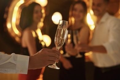 Photo of Man holding glass of champagne at New Year party, closeup