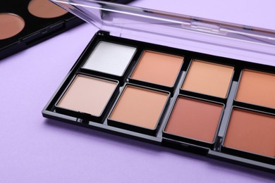 Photo of Colorful contouring palette on violet background, closeup. Professional cosmetic product