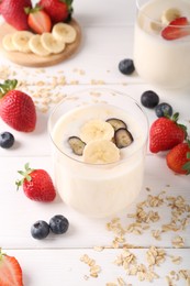 Photo of Healthy break. Composition with tasty yogurt, banana and berries in glasses on white wooden table