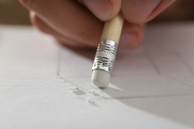 Photo of Man correcting picture on paper with pencil eraser, closeup