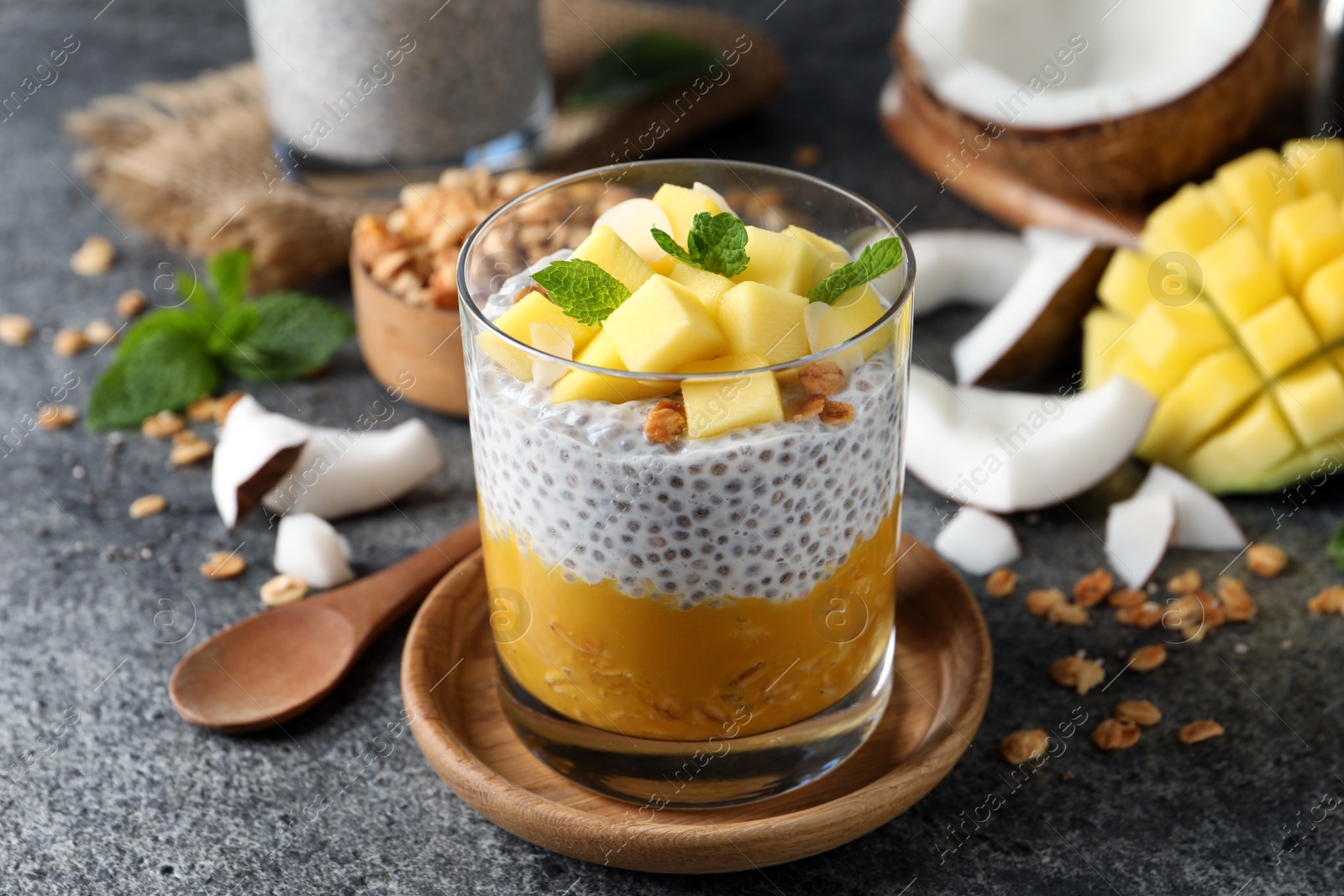 Photo of Delicious chia pudding with mango, mint and granola on grey table