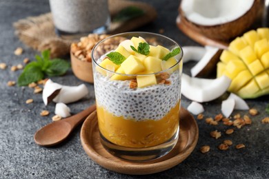 Delicious chia pudding with mango, mint and granola on grey table