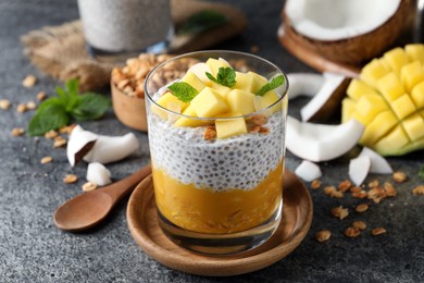 Photo of Delicious chia pudding with mango, mint and granola on grey table