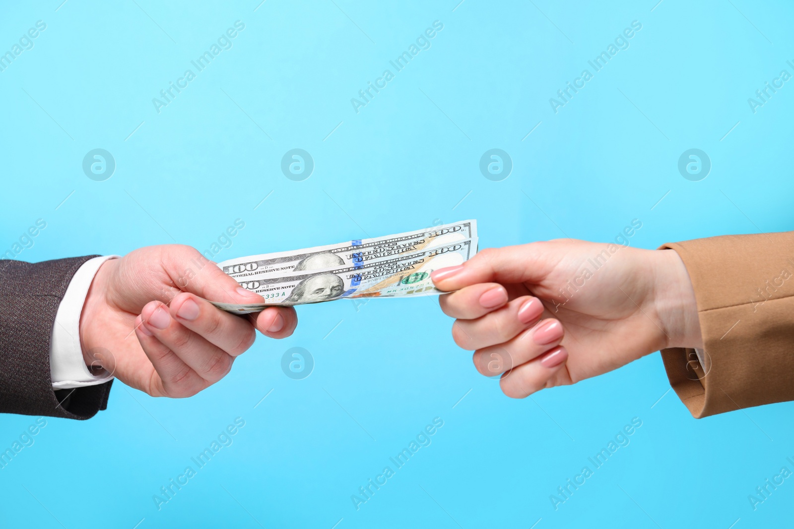 Photo of Man giving money to woman on light blue background, closeup. Currency exchange