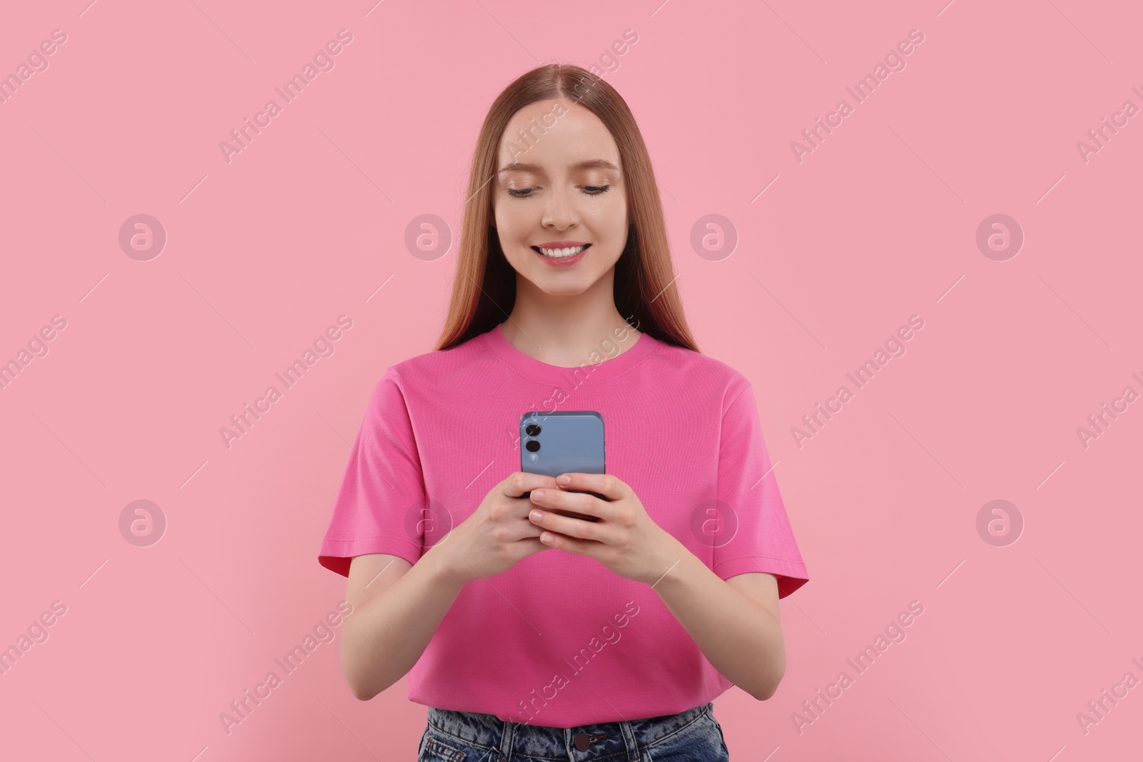 Photo of Happy young woman using smartphone on pink background