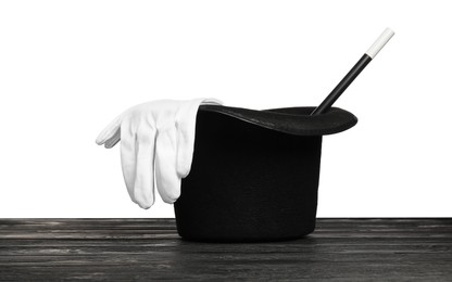 Photo of Magician's hat, gloves and wand on wooden table against white background