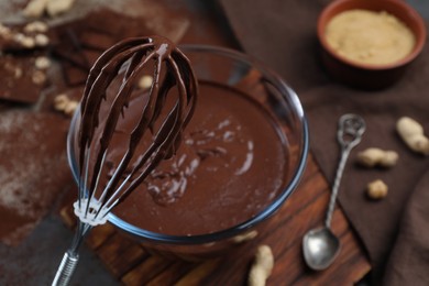 Photo of Whisk with chocolate cream above bowl, closeup