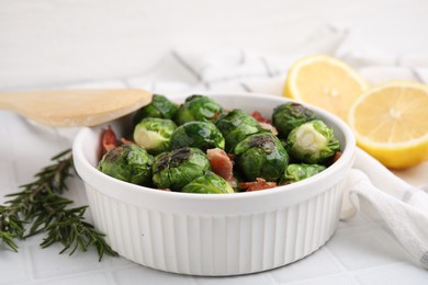 Photo of Delicious roasted Brussels sprouts, bacon and rosemary on white tiled table, closeup