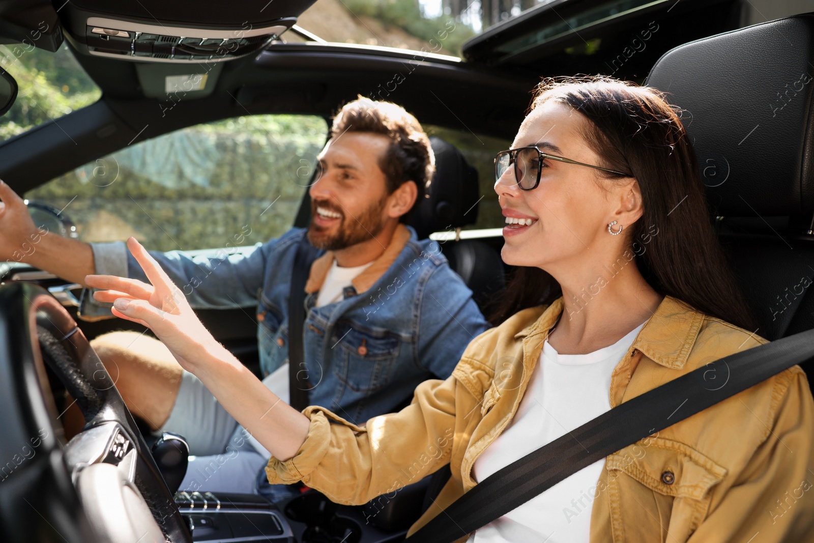 Photo of Happy couple pointing at something while enjoying trip together by car, selective focus