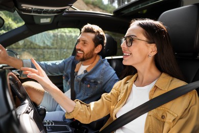 Photo of Happy couple pointing at something while enjoying trip together by car, selective focus