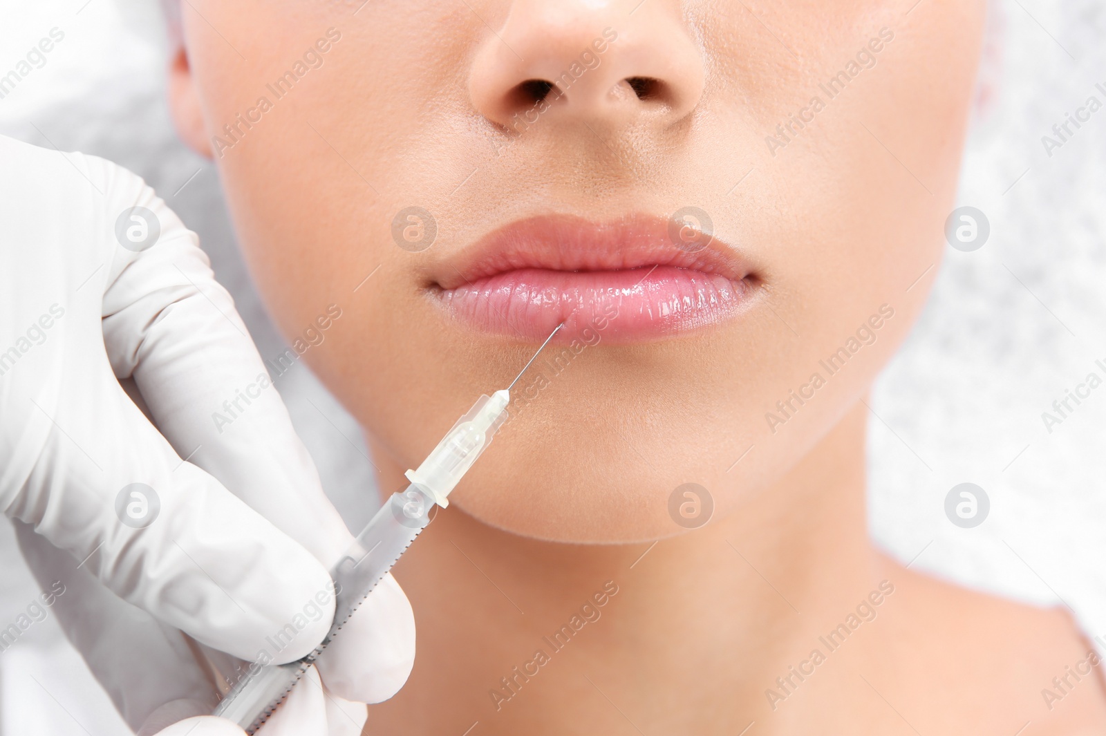 Photo of Young woman getting lip injection in beautician salon, closeup