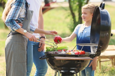 Photo of Happy family having barbecue with modern grill outdoors