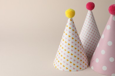 Beautiful party hats with pompoms on beige background. Space for text