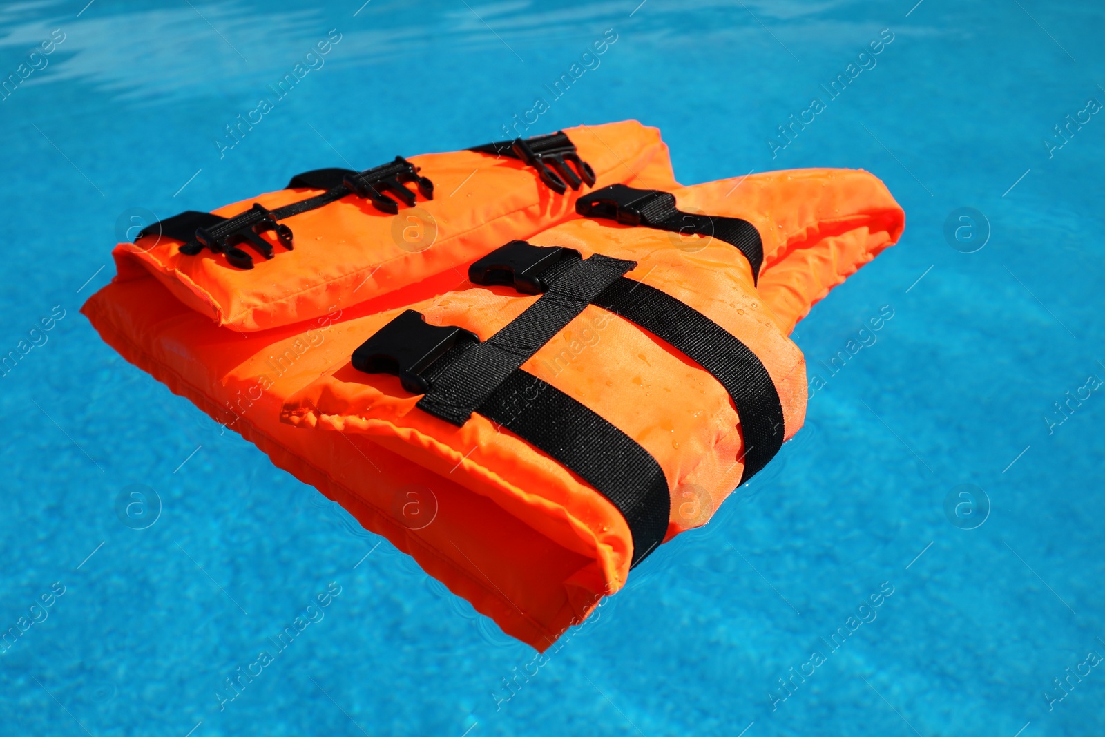 Photo of Bright orange life jacket floating in swimming pool