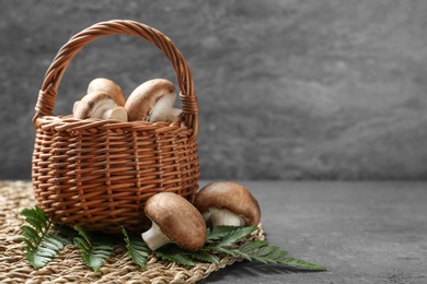 Photo of Wicker basket of fresh champignon mushrooms on table, space for text